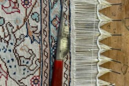 an Oriental rug mid restoration of a damaged fringe