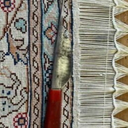 an Oriental rug mid restoration of a damaged fringe