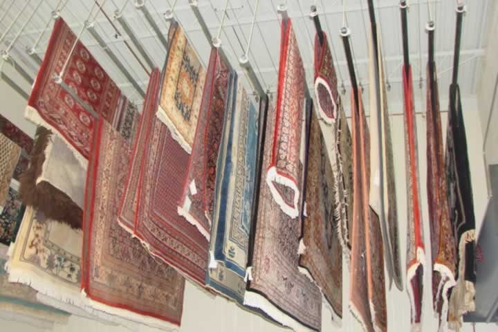 A selection or oriental and persian rugs hanging up to dry after being cleaned and restored